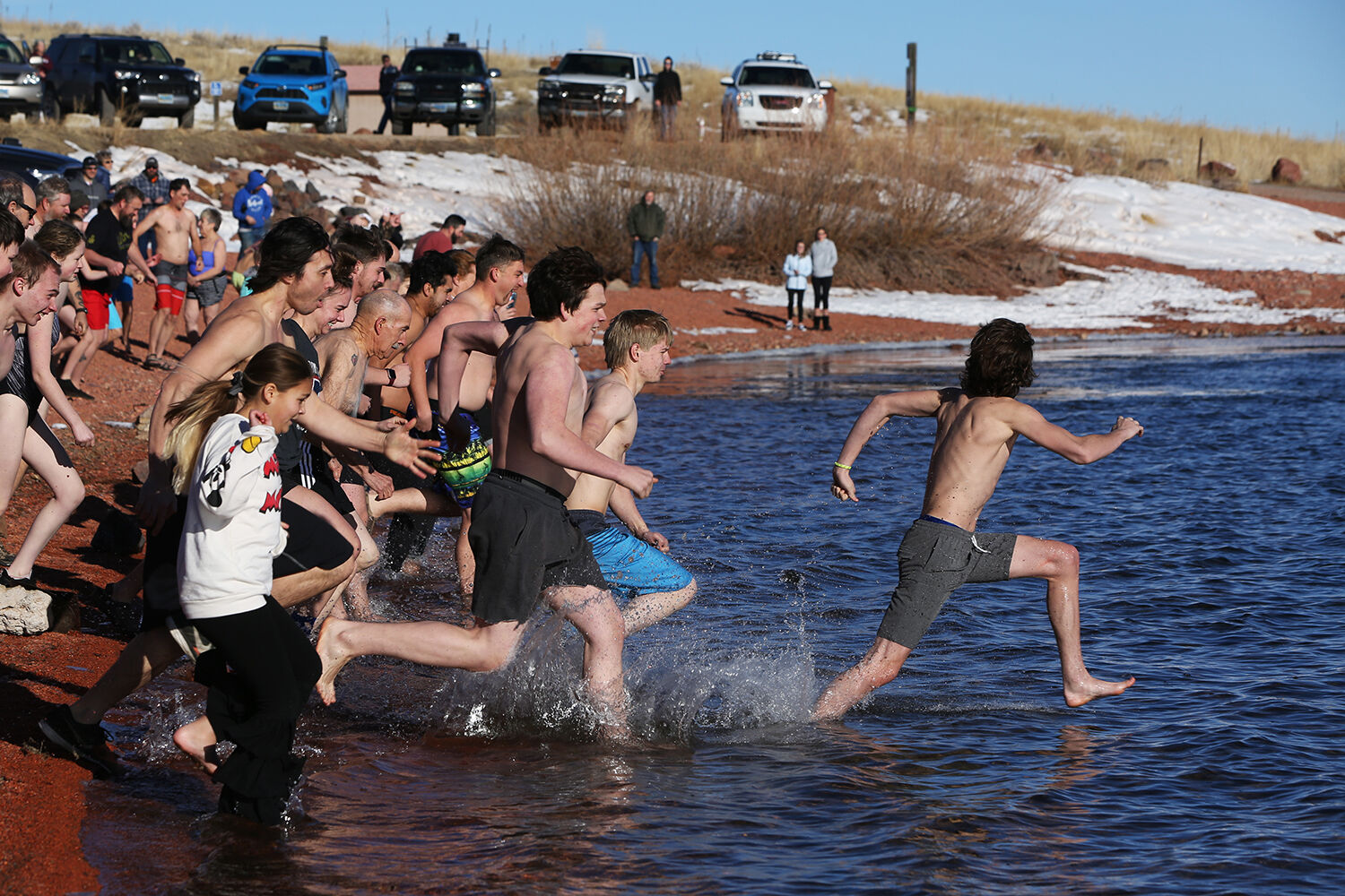 A crowd of people sprint into the cold waters